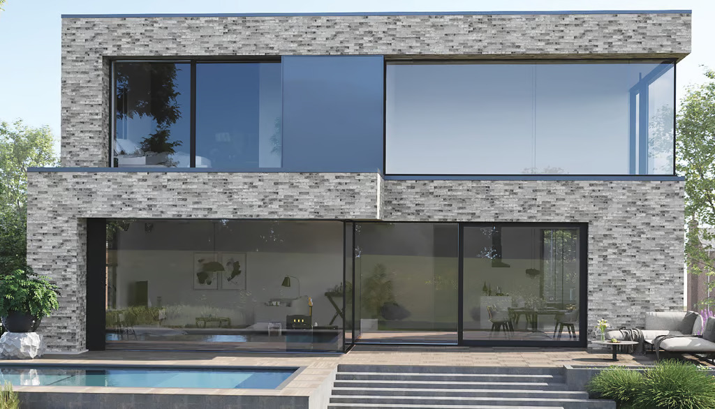 A modern two-story villa with grey brick walls, massive glass windows, and a sleek patio with a swimming pool.